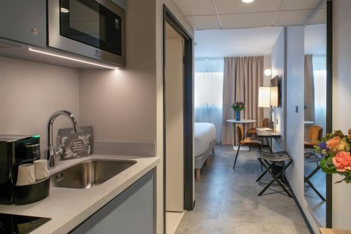 Ein Hotelzimmer mit einer Küchenzeile, einem Bett, einem kleinen Tisch und einem Stuhl.