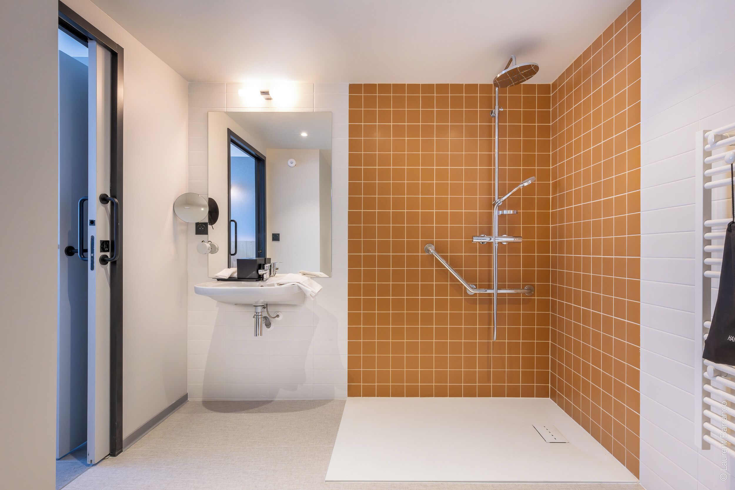 Un baño moderno con ducha, lavamanos y espejo.