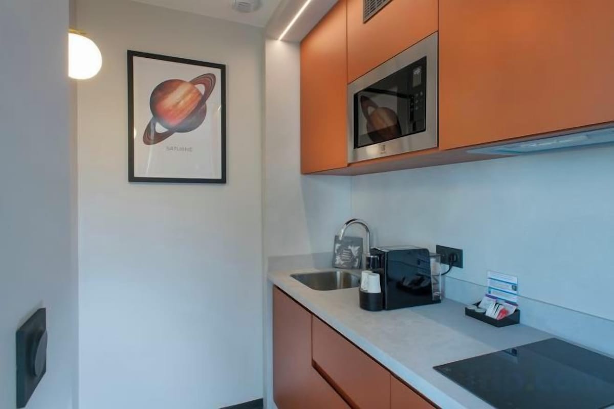 Una cocina moderna con microondas, fregadero y un cuadro en la pared.