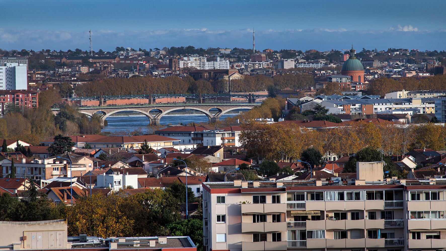 Une vue urbaine mettant en valeur un pont imposant, des immeubles résidentiels et une structure en forme de dôme.
