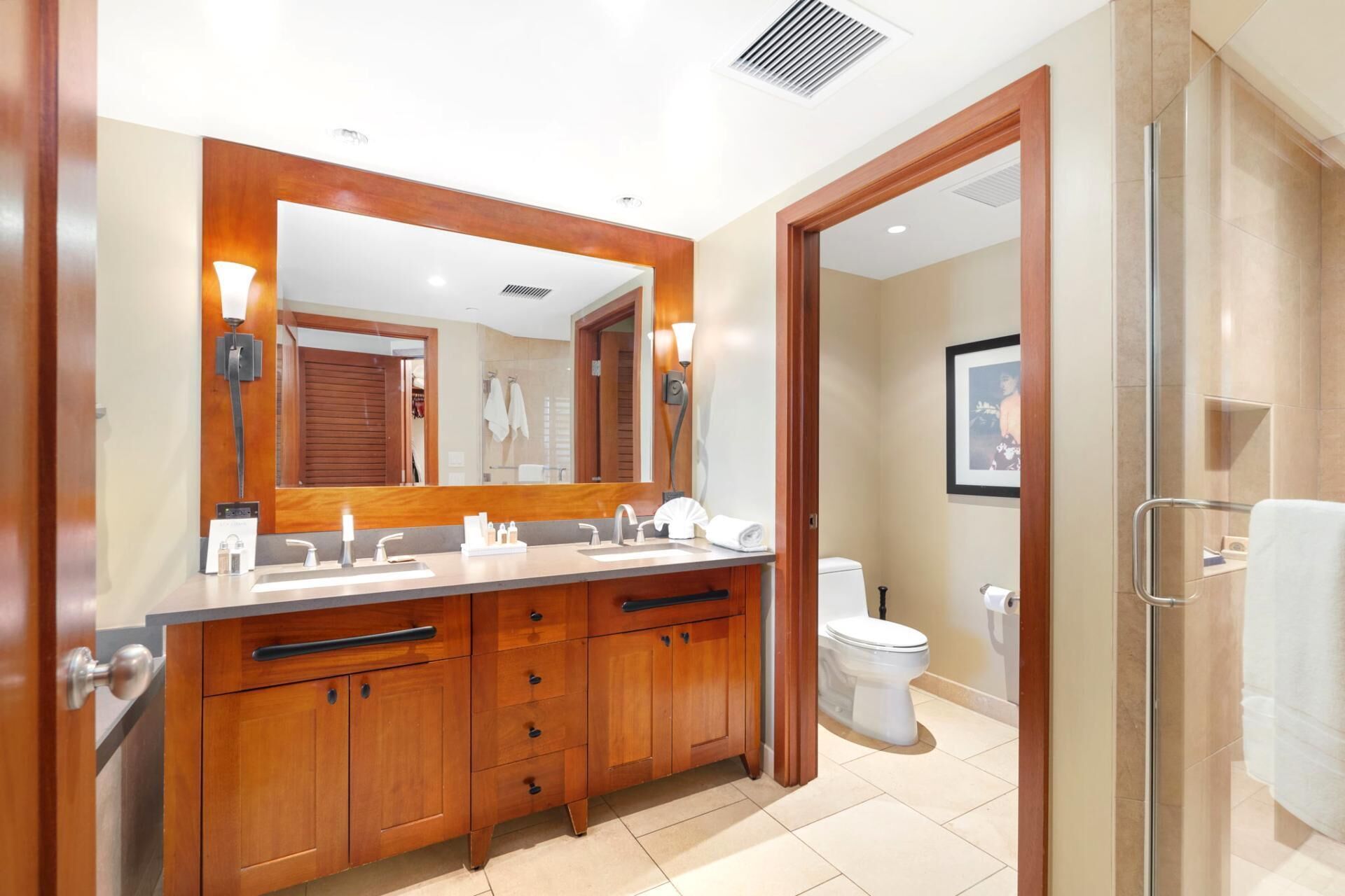 A modern bathroom with a double sink vanity, a large mirror, and a toilet.