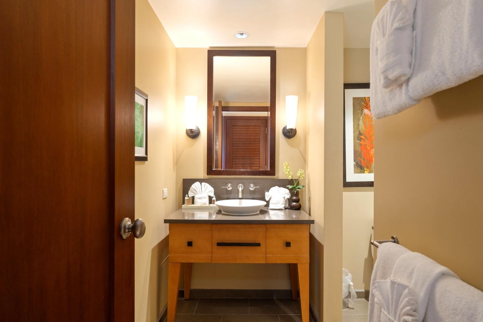 Une salle de bain avec un meuble-lavabo en bois, un grand miroir, deux vasques et un porte-serviettes.