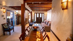 A spacious dining area with a long wooden table, surrounded by chairs, and a modern sofa.