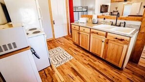 A kitchen with wooden cabinets, a white refrigerator, a sink, and a stove. - Knotty Pine Bunkhouse (Nevada)
