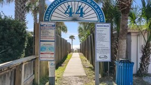 Panneau indiquant l’accès à la plage, avec les règles à respecter et une mention indiquant l’absence de sauveteur.