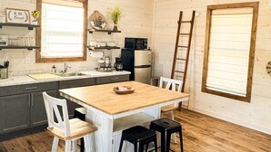 Een keuken met een houten tafel, witte stoelen en een houten plafond.