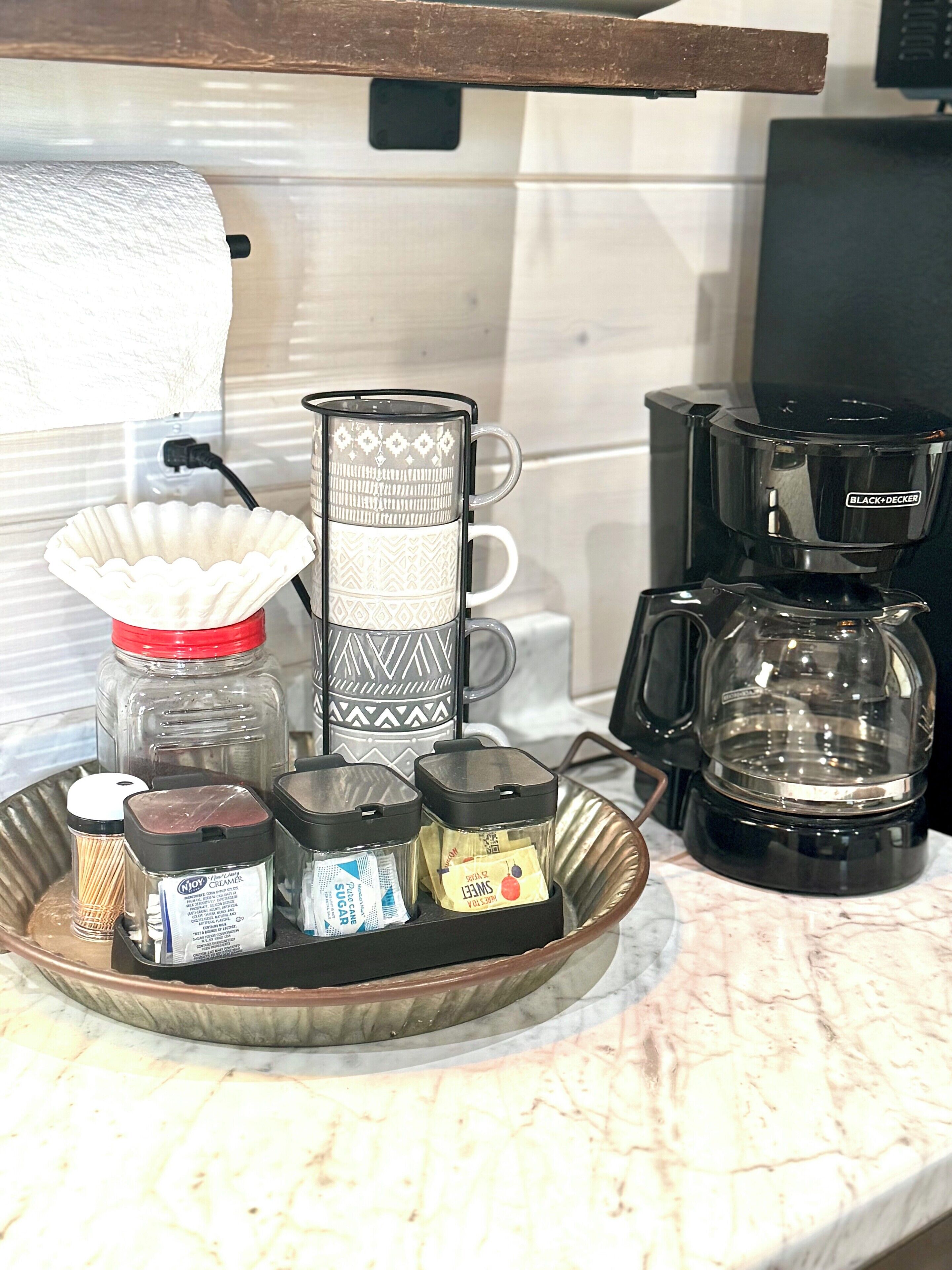 En køkkenbordplade med kaffemaskine, te-udstyr og forskellige krydderier.