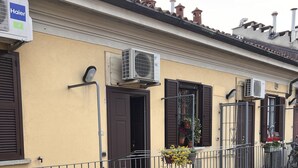 A multi-story building with balconies, air conditioning units, and potted plants. - Cosy centrally located apartment with free of charge garage (Milano)