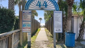 A beach access sign with beach rules and no lifeguard on duty notices.