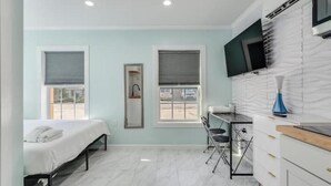 A modern bedroom with a bed, a desk, and a TV.