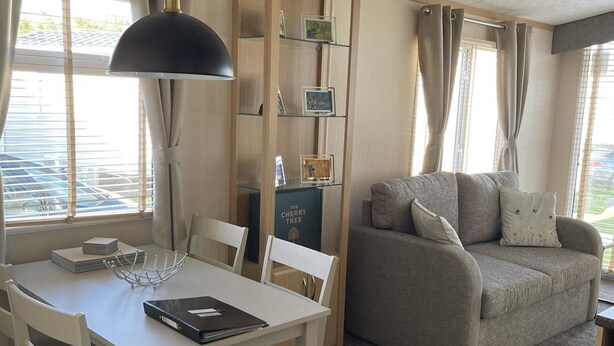 Un salon chaleureux avec une table blanche, un canapé gris et une bibliothèque.