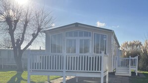 Une maison mobile avec une véranda et une cour clôturée.