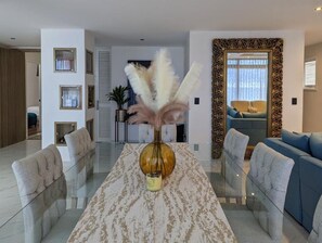 Relax in this stylish living room with a glass-top dining table, tufted sofa, and matching armchair.