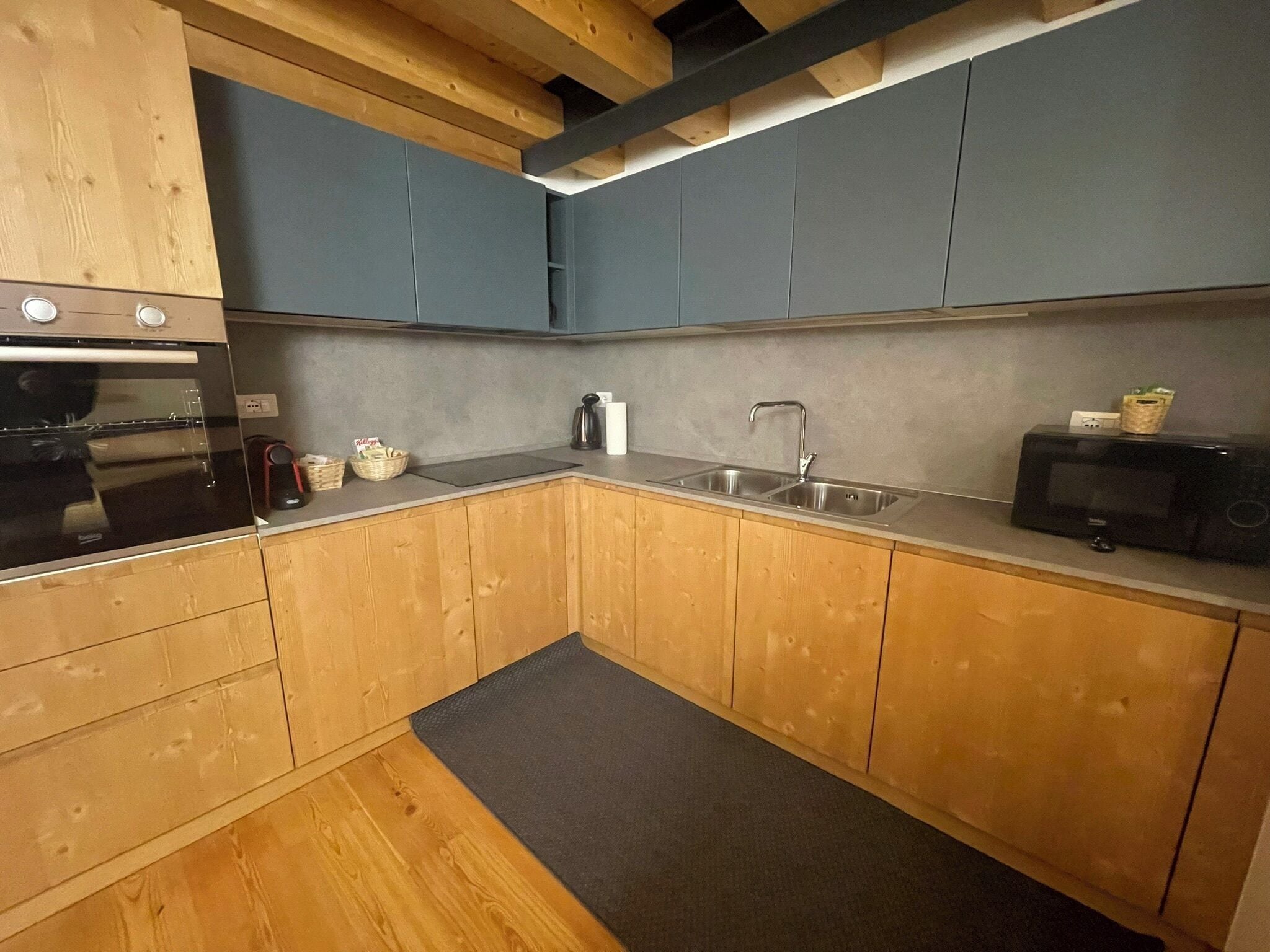 A kitchen with wooden cabinets, a stainless steel sink, a microwave, and a built-in oven.