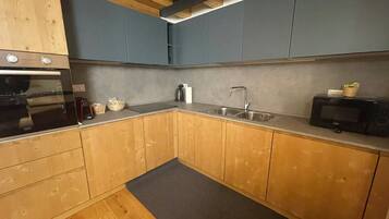 A kitchen with wooden cabinets, a stainless steel sink, a microwave, and a built-in oven.