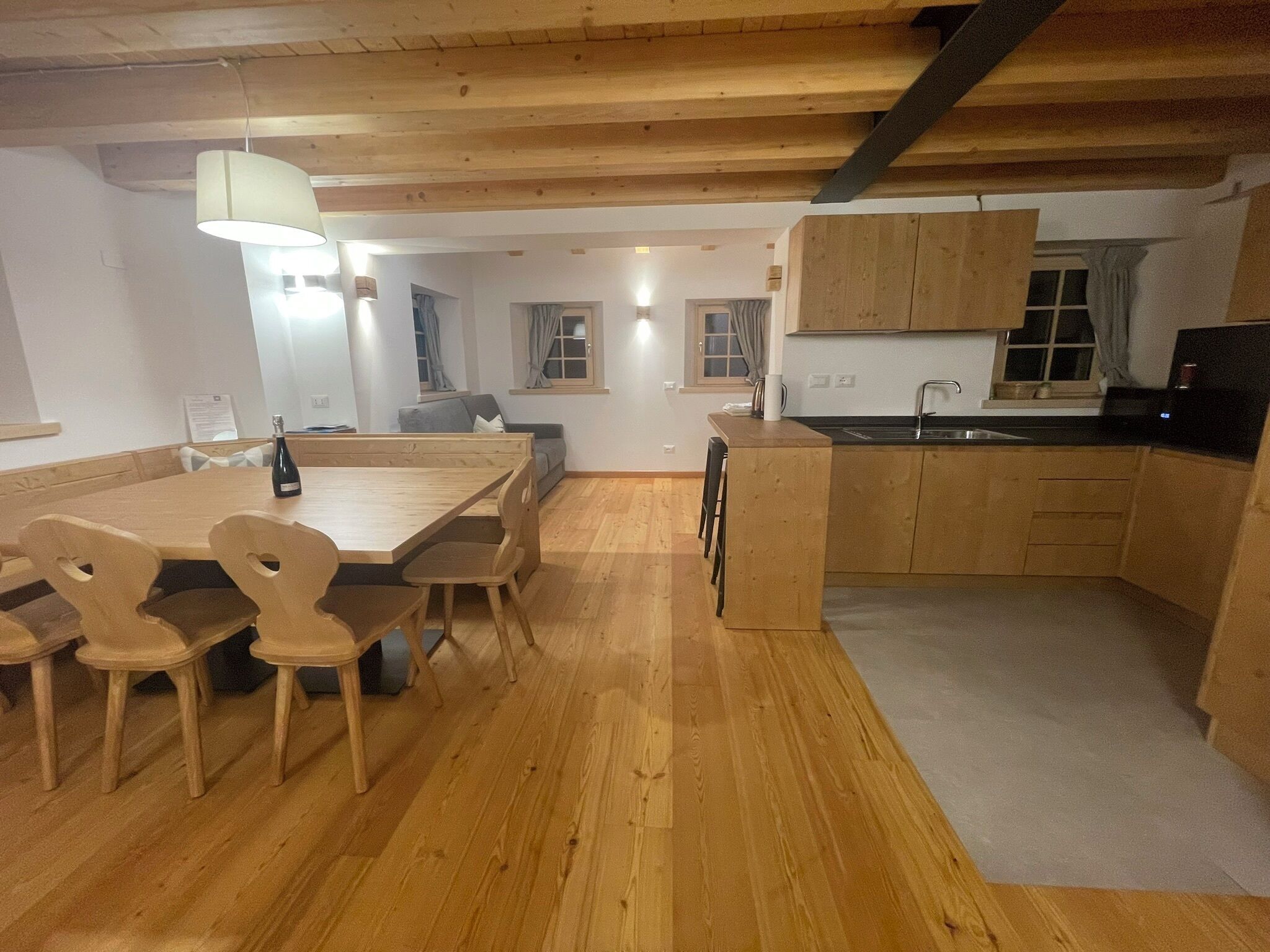 Une cuisine moderne avec des meubles en bois, un coin repas comprenant une table et des chaises en bois, et un petit îlot central doté d’un évier.