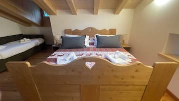Una cama de madera con diseño de corazón, un sofá y una mesita de noche con una lámpara.