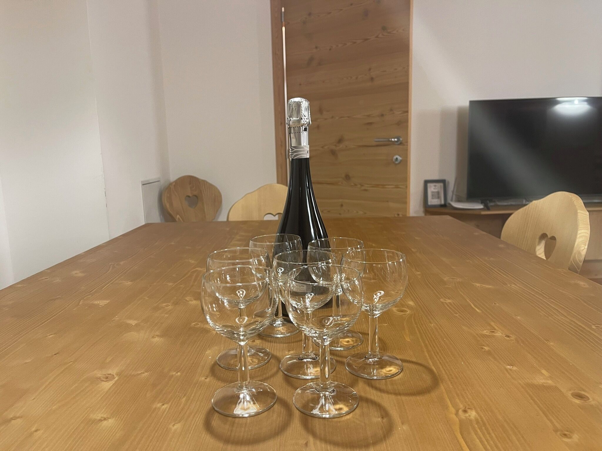 Ein Holzesstisch mit einer Flasche und mehreren Weingläsern.