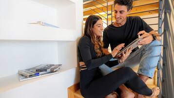 A couple sitting on a wooden staircase, one holding a tablet.