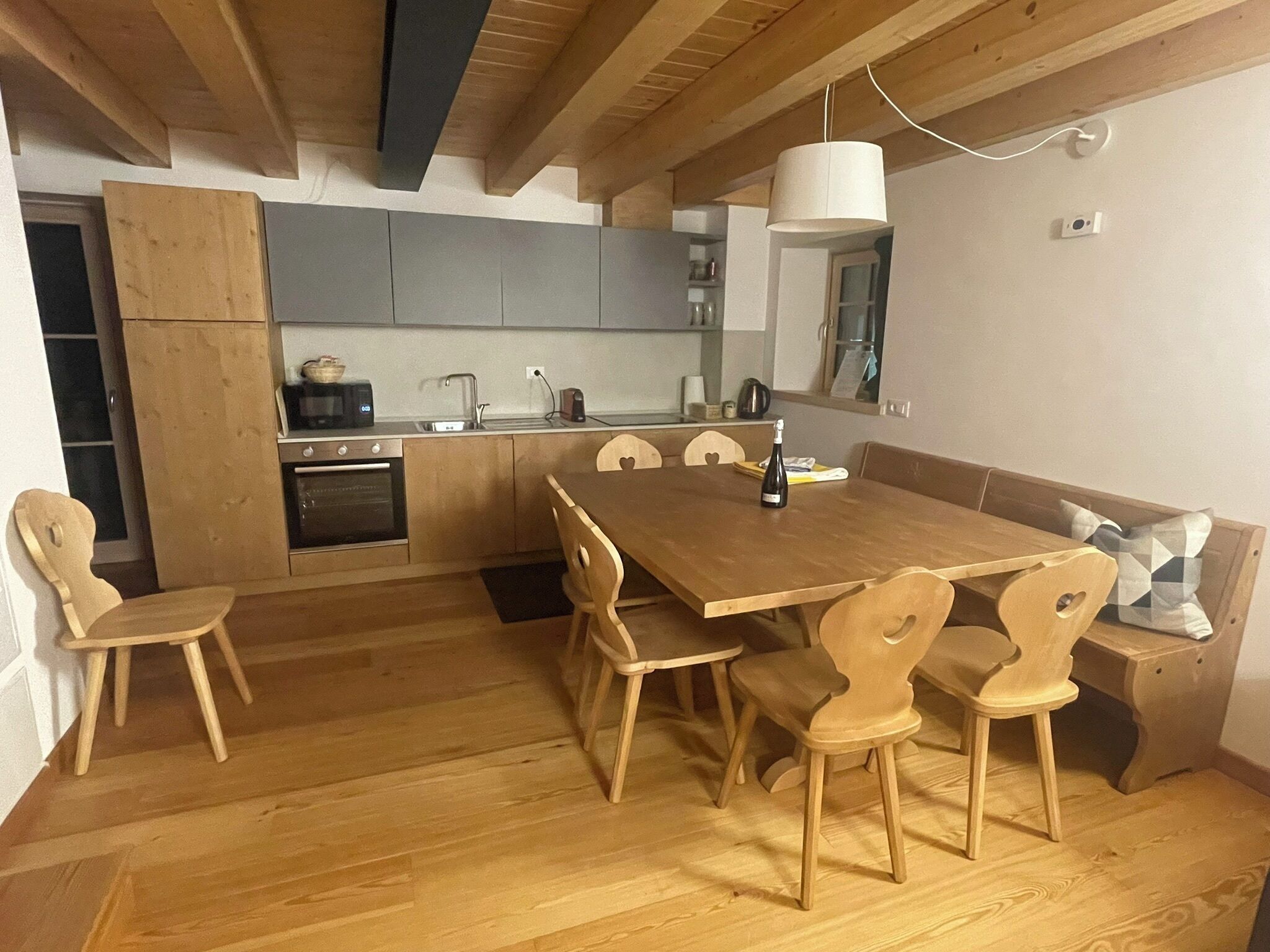 Een moderne keuken met houten kastjes, een eettafel en stoelen.