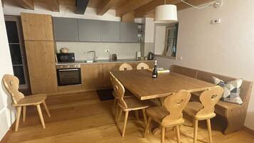 Een moderne keuken met houten kastjes, een eettafel en stoelen.