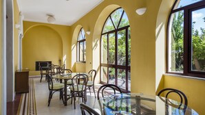 A dining area with arched windows, a glass table, and wicker chairs. - Villa di Charme Vicino al Centro (Lipari)
