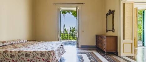 Een kamer met een bed, een dressoir, een spiegel en uitzicht op een balkon.