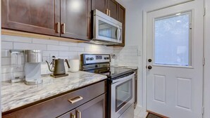 A compact kitchen with dark wood cabinets, a microwave, an oven, and a coffee maker. - Hot Tub - E. Austin - 5 min to UT - 10 min to DT

 (Austin)