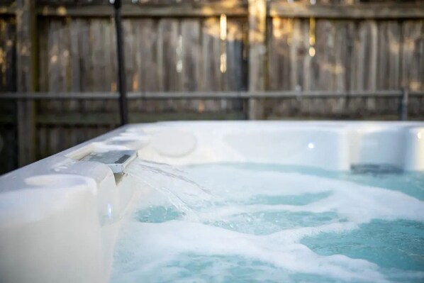 A hot tub with water flowing out, surrounded by a wooden fence.
