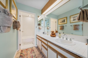 Un bagno con due lavandini, uno specchio, asciugamani e un pavimento in legno.