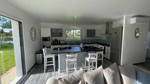 Een moderne keuken met een centraal eiland, witte kasten en een groot raam met uitzicht op de omgeving.