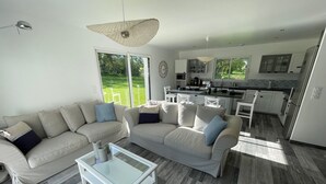 Een moderne woonkamer met een bank, salontafel en een keuken op de achtergrond.