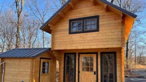 A wooden cabin with a front porch, a small attached shed, and a metal roof. - Après Vine Tiny Cabin at Panther's Rest Farm (Makanda)