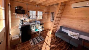 A cozy cabin interior with a kitchenette, a sofa, and a window. - Après Vine Tiny Cabin at Panther's Rest Farm (Makanda)