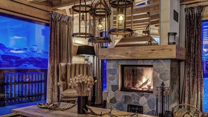 A cozy interior with a stone fireplace, wooden furniture, and a view of a snowy landscape. - Stunning Chalet Adele on the Piste (Veysonnaz)