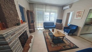 Una sala de estar con chimenea, sofás azules, una mesa de centro y un televisor.