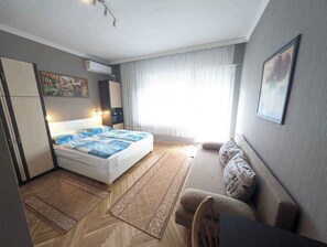 Een knus hotelkamer met een bed, een slaapbank, een stoel en een eettafel.