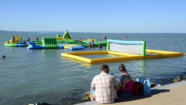 Una playa con estructuras acuáticas inflables y una zona delimitada con red para actividades.
