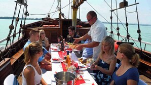 Un grupo de personas cenando en un barco, con una mesa dispuesta para la comida, rodeado de equipo náutico.