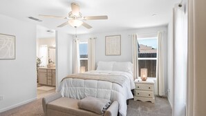 A bedroom with a bed, bedside table, bench, ceiling fan, and window with curtains. - Serenity, a tranquil 4-bed, 3-bath home minutes away from UC Merced.  (Merced)