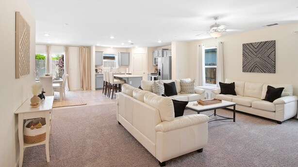 A spacious living room with a white sofa, a coffee table, and a dining area in the background. - Serenity, a tranquil 4-bed, 3-bath home minutes away from UC Merced.  (Merced)