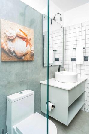 Ein modernes Badezimmer mit Waschbecken, Toilette und Duschkabine aus Glas.