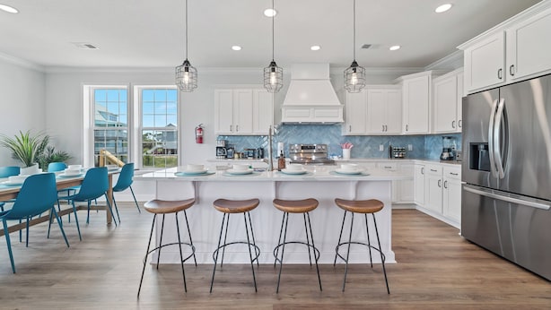 A modern kitchen with white cabinets, a stainless steel refrigerator, and a central island with bar stools. - Private Heated Pool, Fire Pit, 3 King Beds, 3 Min. Walk to the Beach, Dog Fri... (Gulf Shores)