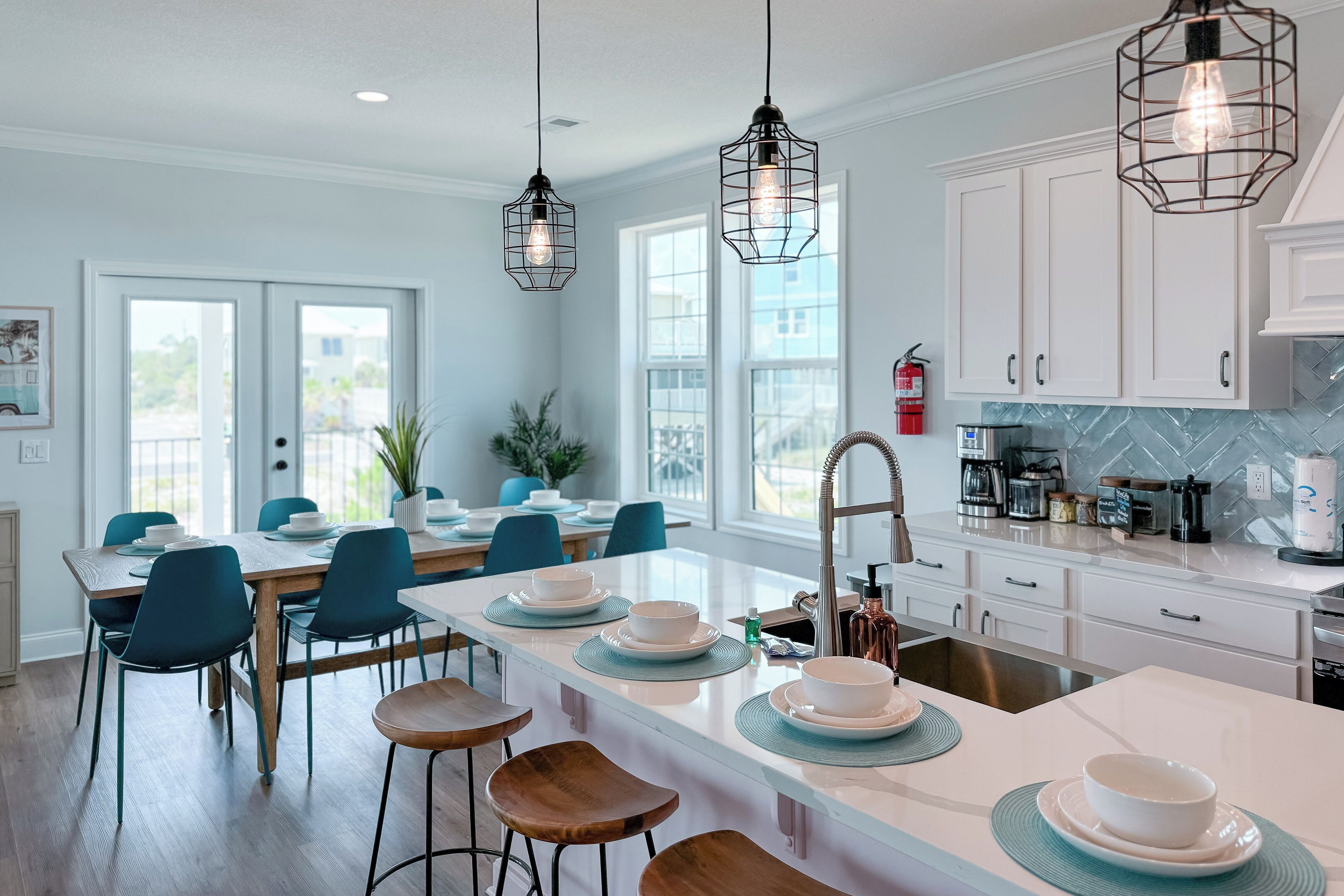 A modern kitchen with white cabinets, a central island with stools, and pendant lighting.