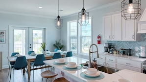 A modern kitchen with white cabinets, a central island with stools, and pendant lighting. - Private Heated Pool, Fire Pit, 3 King Beds, 3 Min. Walk to the Beach, Dog Fri... (Gulf Shores)