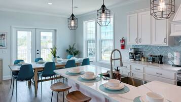 A modern kitchen with white cabinets, a central island with stools, and pendant lighting.