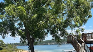 A lakeside outdoor area with picnic tables, a covered seating area, and a wooden deck overlooking the water. - Big fun lake at beaver lake (Rogers)