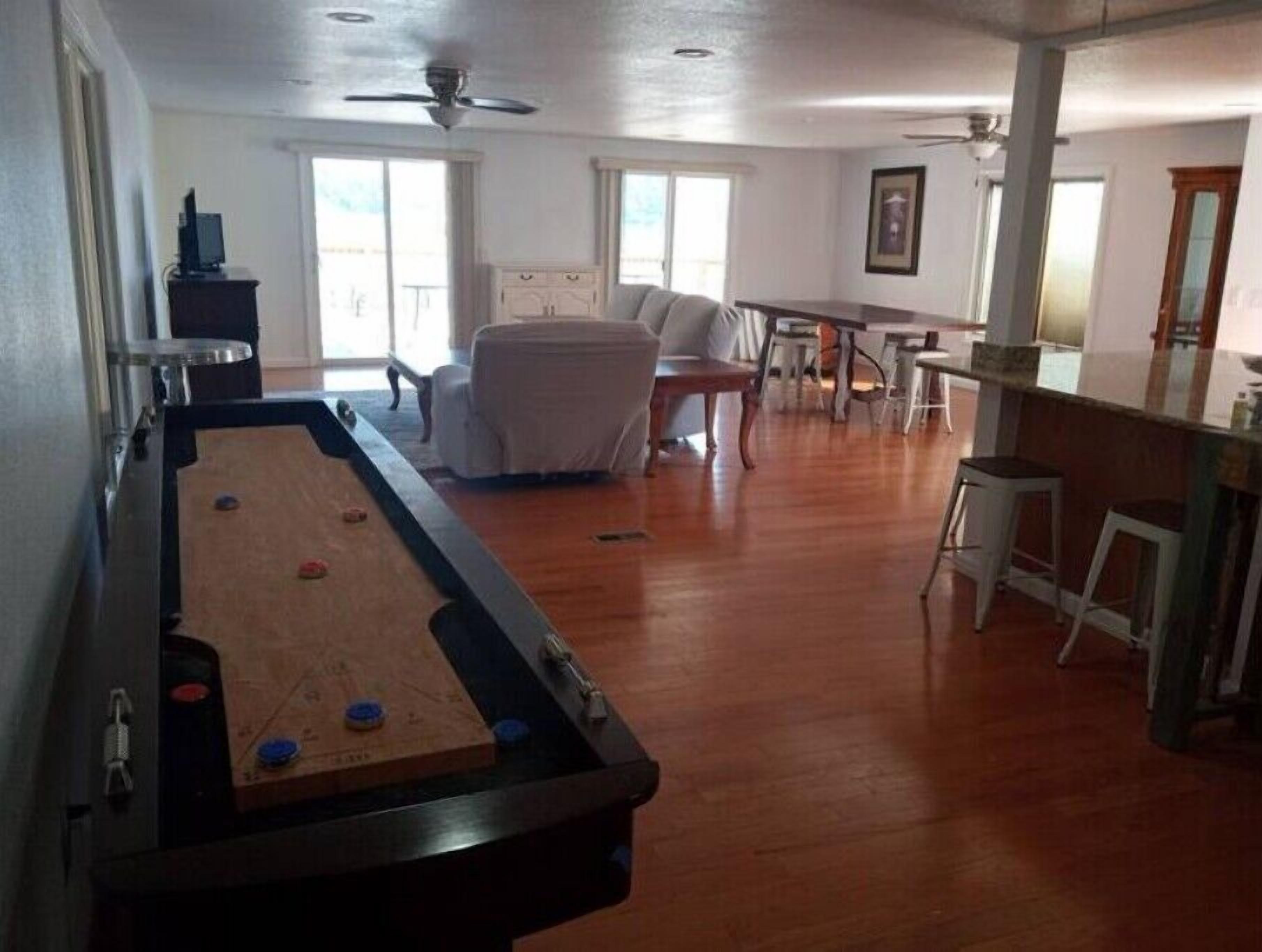 Una mesa de billar en una sala amplia con zona de comedor y bar.