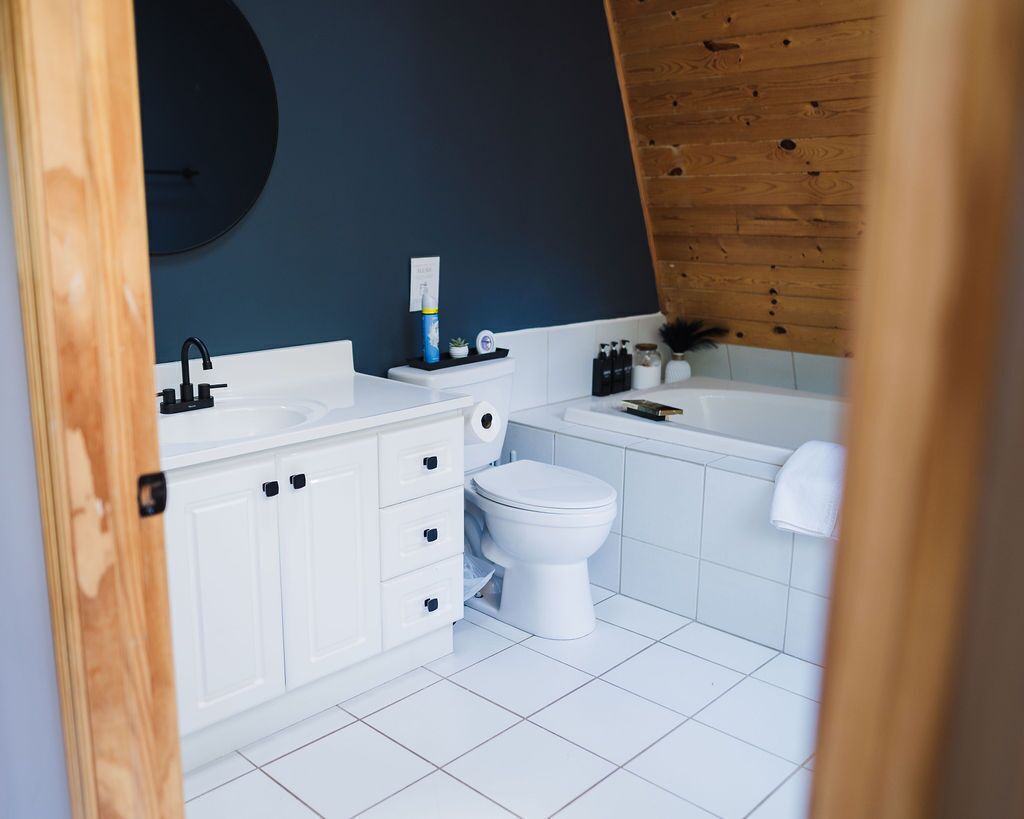 A modern bathroom with white cabinetry, a white toilet, and a bathtub.