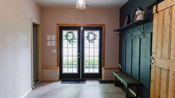 A hallway with a wooden bench, a door with a wreath, and a light fixture.